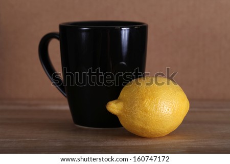 Yellow fresh whole lemon and black coffee mug and yellow lemon still life, shallow focus
