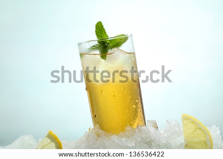 tea frozen with lemon and ice on green background