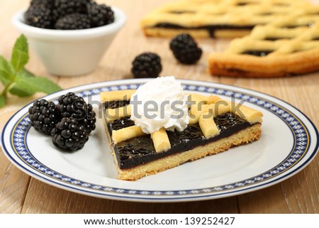 cooked blackberry pie with cream and fruit on plate
