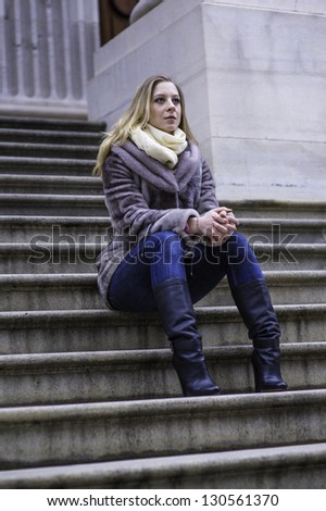 A young woman is sitting on stairs and looking forward./Portrait of Young Woman