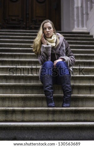 A young woman is sitting on stairs and talking on the phone./Girl Talking on Phone