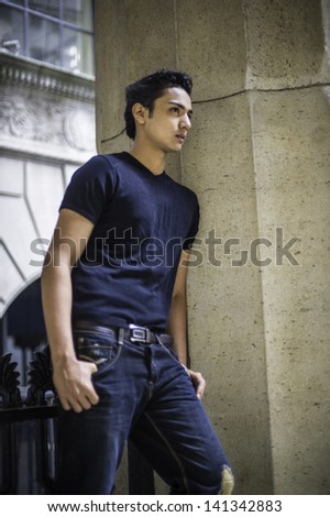 Dressing in black T shirt and  fashionable pants, leaning on a column, a young attractive asian teenager is thinking outside./Thinking Outside