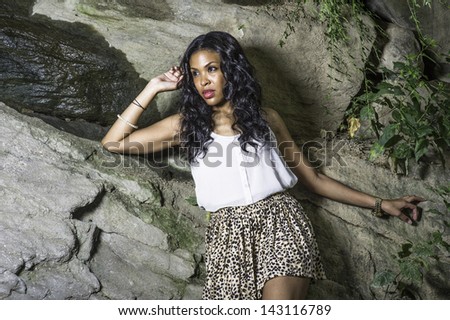 A pretty black girl relies on rocks, with spring water on rocks, thoughtfully looking forward./Waiting for You