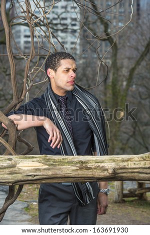 Dressing in a black shirt, tie and long scarf, a young handsome guy is pondering at small woods and into deeply thinking. / Deeply Thinking