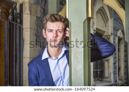 Dressing in a blue jacket and a light blue under shirt, a young handsome guy is standing by a column at a cottage,  sincerely looking at you /Portrait of Young Guy