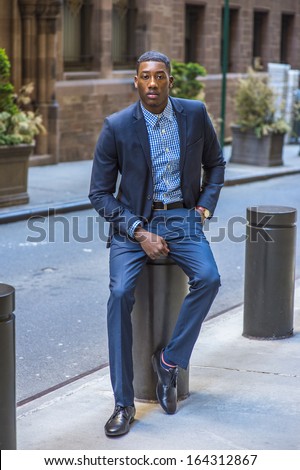 A young black businessman is sitting on the street and taking a break / Portrait of Young Black Businessman