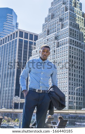 Taking off his jacket, a young black businessman is standing in the front of a busy business district, looking at you. / Portrait of Young Businessman,