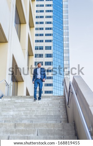 Holding a tablet computer, a young handsome black businessman is walking down stairs outside of a business building, confidently looking forward. / Portrait of Young Black Businessman