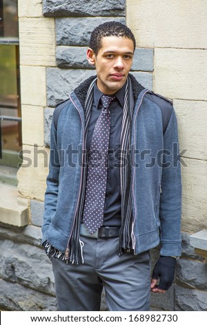 Dressing in woolen jacket with shoulder pads, tie, long scarf and gloves, a young handsome guy is standing against the wall, charmingly looking at you / Waiting for You