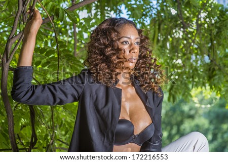 Sweat running on her face, a young sexy black girl with curly long hair is under trees in summer, cooling down and relaxing. /Cooling Down