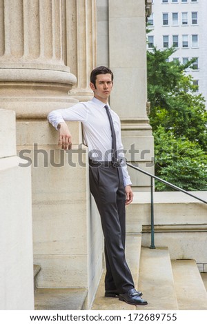 Dressing in a long sleeve white shirt, black pants, leather shoes, a black tie, a young layer is standing outside a office building, relaxing and thinking. / Portrait of Young Businessman