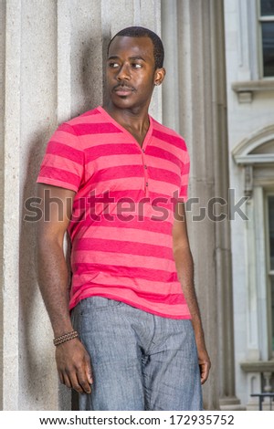 Dressing in red, pink stripe Henley V Neck T shirt,  gray pants, wearing a bracelet, a young black guy is standing by a pillar, confidently looking forward. / Portrait of Young Black Guy