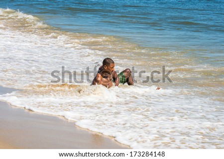 A  young black guy, half naked,  is sitting on water of the beach, relaxing / Relaxing on Beach