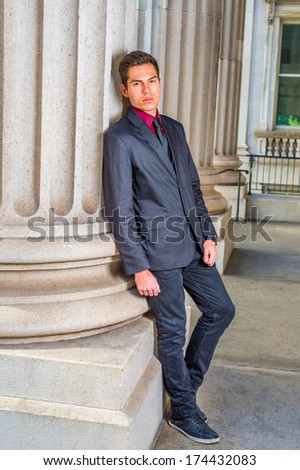 Dressing in a red undershirt, a black blazer, black jeans and a black tie, a college student is leaning against a column outside a office on the campus, relaxing and thinking. / Thinking Outside