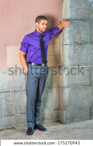 Dressing in purple shirt, gray pants, black tie,  one hand putting in a pocket, one arm resting on the wall, a young businessman with a little beard and mustache is standing in the corner,  thinking.