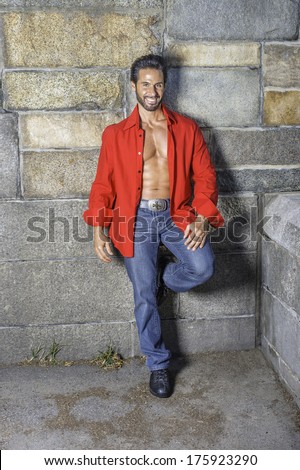 Dressing in a red long sleeve shirt, unbuttoned, blue jeans, leather shoes, a sexy, middle age guy with mustache and beard is leaning against the wall, smilingly looking at you. / Personal Trainer