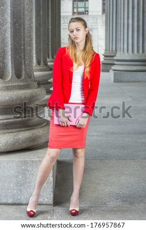Dressing in a red blazer, white under wear, a red skirt, open toes high heels, holding a tablet computer, a female college student is standing outside an office building. / Portrait of College Student