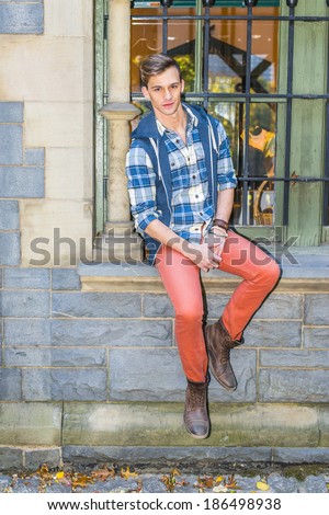 Young Man Relaxing Outside. Dressing in a blue and white pattern shirt,  a blue hood vest,  red jeans and brown leather boot shoes, a young guy is sitting on the frame of the window, waiting for you.