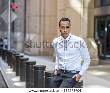 Man Waiting for You. Dressing in a white shirt, two hands putting in pockets, a young guy is sitting on the street, relaxing, looking at you.