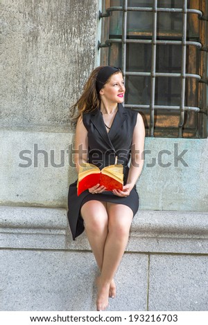 Sexy Woman Reading Outside. Wearing a black sleeveless trench coat dress, a hair band,  a young beautiful woman, barefoot, is sitting by a window, smiling, looking up, reading a red book.