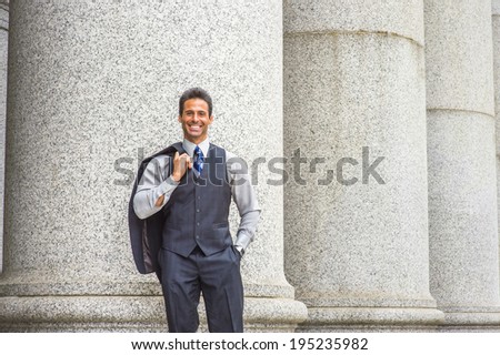 Man Relaxing Outside. Wearing a light gray shirt, dark blue vest, necktie, jacket taken off on shoulder, a  handsome, middle age businessman is standing by columns outside,  smiling, looking at you.