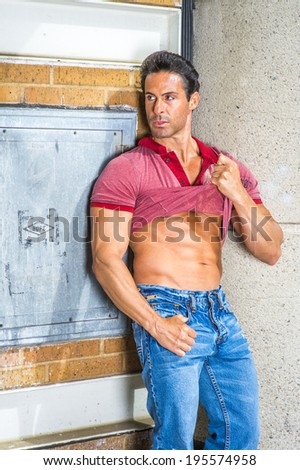 Strong Man. Holding on his shirt, a handsome, sexy, middle age guy is standing in the corner of the street, looking aside, confidently showing his success, hope, belief. Relaxing outside