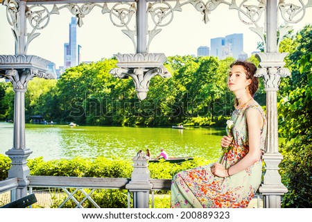 Young Lady Waiting  for You. Dressing in sleeveless, long dress, a pretty teenage girl is sitting inside a pavilion, hands holding a white rose, looking at you. people rolling boats in background,.