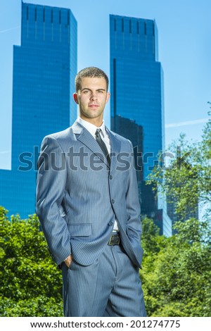Portrait of young business man. Dressing formally in a blue suit, black tie, a young professional guy is standing in the front of business district, seriously looking at you.