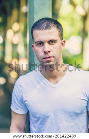 Portrait of young man, wearing a white V neck T shirt,  short hair.