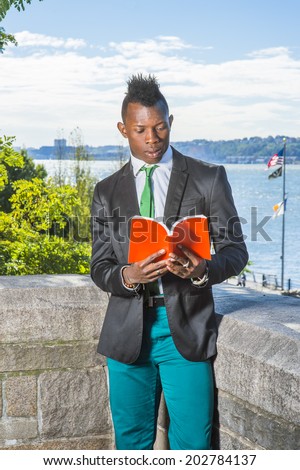 Man Reading Outside. Dressing in a white undershirt, a black blazer, green pants, a green tie, holding a red book,  a young black guy with mohawk haircut is standing by a river,  reading outside.