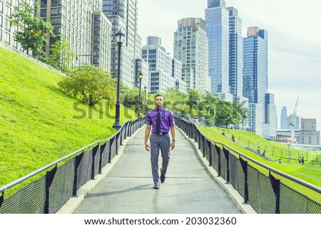 Road to Success. a young handsome man is confidently walking down on a road from a busy business district.