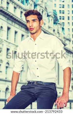 Young Businessman. Wearing a white shirt, black pants, a young college student is sitting in the front of business district, confidently looking forward.