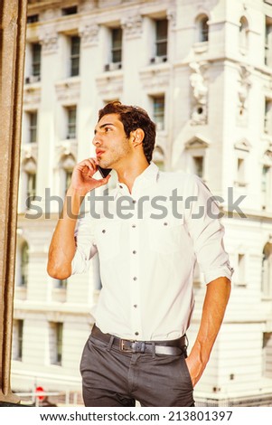 Young Businessman Calling Outside. Wearing a white shirt, black pants, a young college student is talking on a mobile phone outside an office building.