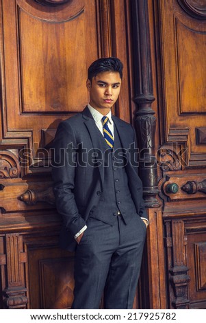Portrait of Young Business Man. Dressing in a black suit, patterned  necktie, vest, hands in pockets,