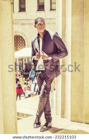 Young black man thinking outside. Wearing a white under wear, fashionable jacket, a young black college student is standing by columns, confidently looking forward. Street Fashion.