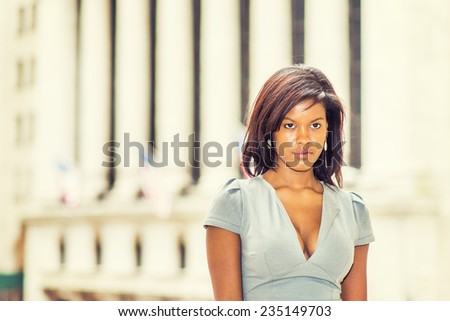 Portrait of Young Black Girl. Wearing a gray business dress, a young beautiful black woman is standing outside an office building, thinking.