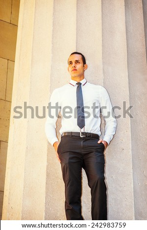 Businessman Thinking Outside. Dressing in a white shirt, a black tie, hands in pockets, a young handsome guy is standing outside a office building, lost in thought.