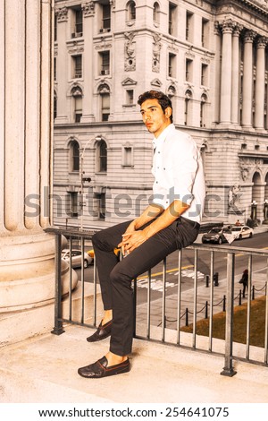 Businessman. Wearing a white shirt, black pants, leather shoes, a young college student is sitting on a railing in a business district, relaxing, thinking. Man Casual Fashion. Vintage filtered look.
