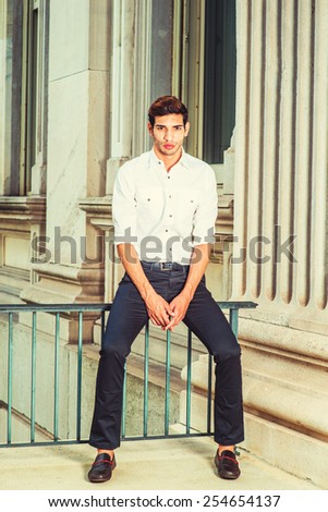 Man Casual Fashion. Wearing white shirt, sleeves rolling over, black pants, leather shoes, a college student sitting on a railing outside office building, relaxing, thinking. Instagram filtered look.