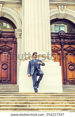 Time is Money. Dressing in dark blue suit, necktie, bending a leg, a handsome, sexy, middle age guy standing in front of office building, looking at watch, waiting for you. Instagram filtered look.