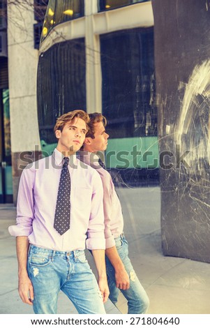 Reflection. Young blonde, handsome guy, wearing long sleeve, pink shirt, necktie, jeans, leaning against a metal mirror wall, looking up, lost in thought. I missing You. Instagram filtered effect.