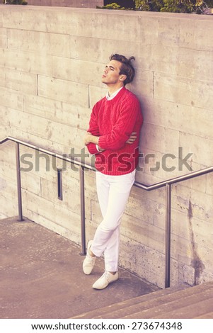 Urban Fashion. Young blonde professional, wearing red sweater, white pant, casual fashion shoes, crossing arms, leaning back against wall, sad, thinking, lost in thought, Retro filtered look.