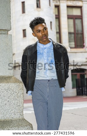 School Boy. A 18 years old student, wearing black fashionable leather, wool mixed jacket, striped pants, blue dyed white shirt, standing by gate on campus, hands in back, interestedly looking around.