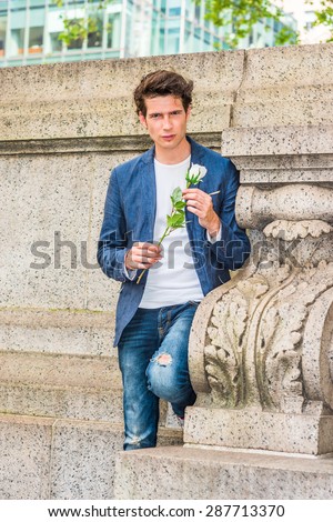 European college student seeking love in New York. Wearing blue blazer, jeans, a young guy standing at corner against wall on campus, hands holding white rose, thinking, missing you, waiting for you.