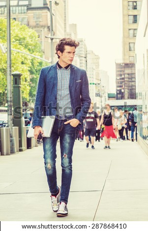 European College Student Studying in New York. Wearing blue blazer, jeans, sneakers, holding laptop computer, a young guy confidently walking on street in sunny afternoon. Instagram filtered effect.