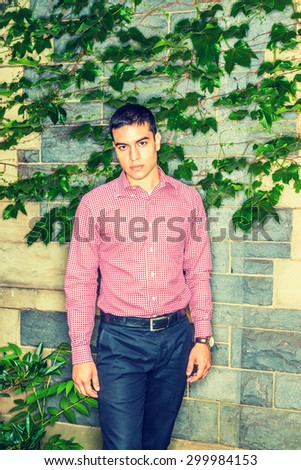 College Student. Man casual fashion. Wearing red patterned, long sleeve shirt, black pants, wristwatch, young guy standing against wall with ivy leaves, confidently looking forward. Instagram effect.