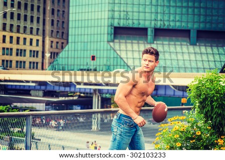 Play Hard, Work Smart. Shirtless, half naked, waring jeans, a young, strong, sexy businessman, carrying football, running from business district in New York, enjoying outdoor activities after work.