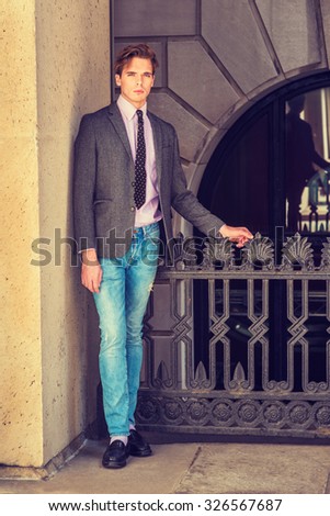 Serious American businessman in New York. Wearing blazer, necktie, jeans, leather shoes, a young college student standing by railing on balcony outside, waiting for you. Instagram filtered effect.