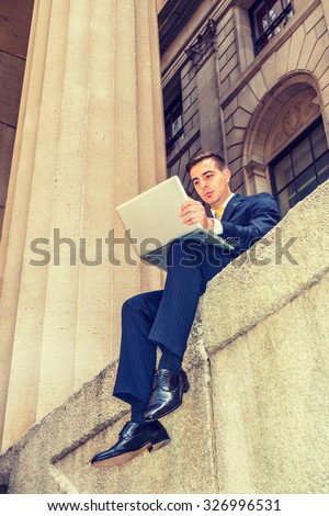 Businessman with little scar on lip - cleft lip, dressing in blue suit, yellow tie, working on laptop computer. Concept of facing reality, up and down, self assured, self esteem, confidence, success.