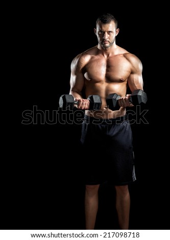 Young adult man doing barbell press in gym. Black background. Gym training workout.